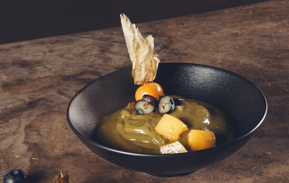 Mango mousse decorated with Aguaymanto and nicely served in a black ceramic bowl at Green Point Restaurants Cusco.